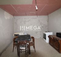 Unvollendete Küche in einem Einfamilienhaus mit einfach eingerichteten älteren Geräten und Möbeln.