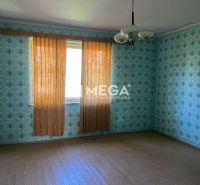 Ein Zimmer in einem Einfamilienhaus mit gemusterten Tapeten und einem Boden in Holzoptik.