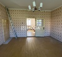Ein Zimmer in einem Einfamilienhaus mit einem Boden in Holzoptik und gemusterten Tapeten.