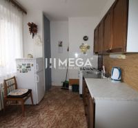 Küche in einer 2-Zimmer-Wohnung mit Kühlschrank, Holzboden, hellem Vorhang.