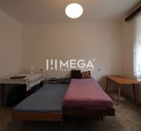 Schlafzimmer in einer 2-Zimmer-Wohnung mit Bett, Tisch und Boden in Holzoptik.