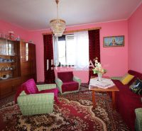 Wohnzimmer mit rosa Wänden, Sitzgarnitur, Vitrine und Kronleuchter in einem Einfamilienhaus.