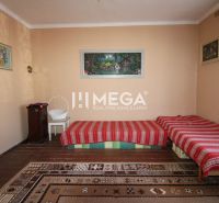 Ein Zimmer in einem Einfamilienhaus mit Teppichen, Betten und einem stehenden Ofen.
