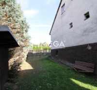 Garten bei einem Einfamilienhaus in der Volica-Straße in der Stadt Volica mit einer Bank und Nadelbäumen.