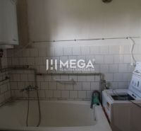 Ein Badezimmer in einem Einfamilienhaus mit einer Badewanne und einer Waschmaschine, umgeben von weißen Fliesen.