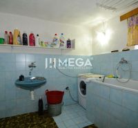 Ein Badezimmer in einem Einfamilienhaus mit Badewanne, Waschbecken und Waschmaschine, ausgestellte Reinigungsmittel.