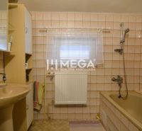 Badezimmer in einem Einfamilienhaus mit beigen Fliesen, einer Badewanne und einem Waschbecken.