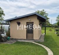 Ein Einfamilienhaus in Lackovce mit gepflegtem Rasen, Garten und einem kleineren Gebäude im Hintergrund.