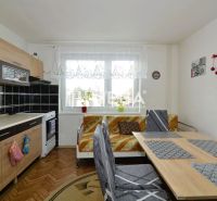 Küche in einem Einfamilienhaus mit Küchenzeile und Esstisch, Boden mit Holzdekor.