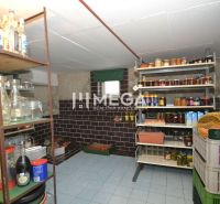 Speisekammer mit Regalen voller Einmachgläser in einem Einfamilienhaus, mit Steinen verkleidete Wände und Fliesenboden.