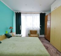 Ein Schlafzimmer in einem Einfamilienhaus mit einer türkisfarbenen Wand, einem großen Bett und Schränken.