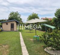Der Garten des Einfamilienhauses in Lackovce mit Rasen, Sitzbereich und einem kleinen Bauwerk.