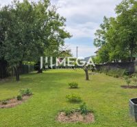 Gartenbereich eines Einfamilienhauses in Lackovce mit Rasen und Bäumen.