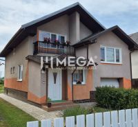 Ein Einfamilienhaus in Lackovce mit Balkon, umgebender Vegetation und einem weißen Zaun.
