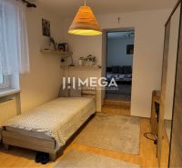Ein Zimmer in einem Einfamilienhaus mit Bett, Teppichen und Holzboden.
