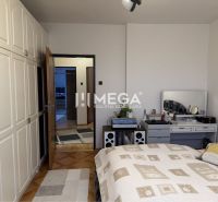 Schlafzimmer in einem Einfamilienhaus mit weißem Kleiderschrank und dekorativem Tisch hinter dem Bett.