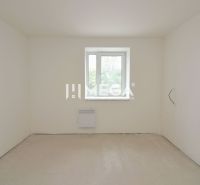 Ein leerer Raum in einer 3-Zimmer-Wohnung mit weißen Wänden und einem hellen Fenster.