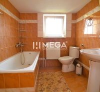 Badezimmer in einem Einfamilienhaus mit Badewanne, Waschbecken und orangefarbenen Fliesen.