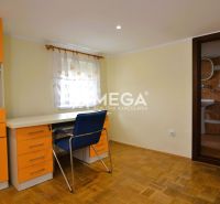Ein Zimmer in einem Einfamilienhaus mit orangefarbenen Möbeln und einem Boden in Holzoptik.