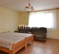 Schlafzimmer mit Bett, Sofa und Holzboden in einem Einfamilienhaus.