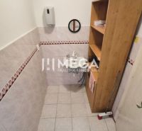 Badezimmer in Geschäftsräumen mit Waschbecken, Regalen und Fliesen an den Wänden.