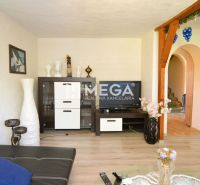 Wohnzimmer in einem Einfamilienhaus mit Holzboden, Wand mit Bildern und Fernseher.