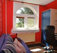 Ein Zimmer in einem Einfamilienhaus mit roten Wänden, Teppich, Fenster, Sofa und Schreibtisch.