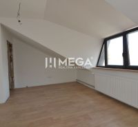 Dachzimmer mit weißen Wänden und Holzboden in einer 2-Zimmer-Wohnung.