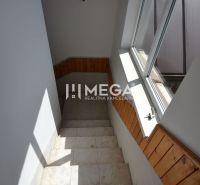 Eine Treppe mit Holzverkleidung und einem großen Fenster in einer Zweizimmerwohnung.