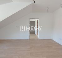 Ein Zimmer in einer 2-Zimmer-Wohnung mit weißen Wänden und einem Boden in Holzoptik.