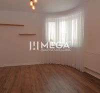 Ein Zimmer in einem Einfamilienhaus mit einem Boden in Holzoptik, weißen Wänden und Vorhängen.