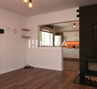Innenraum eines Einfamilienhauses mit Kamin, Holzboden und Blick in die Küche.