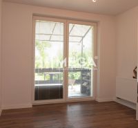 Ein Zimmer mit Holzboden, großes Fenster, Heizkörper, Spiegel. Ein Einfamilienhaus.