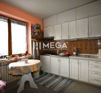 Eine Küche in einem Einfamilienhaus mit weißen Schränken und Blumendekoration an der Wand.