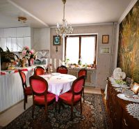 Esszimmer in einem Einfamilienhaus mit Vintage-Möbeln, großer Tapete und Dekorationen auf Holzschränken.