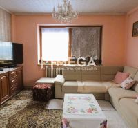 Wohnzimmer in einem Einfamilienhaus mit Ecksofa, Teppich und Fernseher auf einem Schrank.