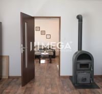 In einem Einfamilienhaus gibt es einen Ofen, Schränke, Türen und einen Boden mit Holzdekor.