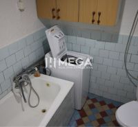 Ein Badezimmer im Einfamilienhaus mit Badewanne, Waschmaschine und Toilette, gefliest.