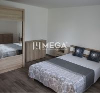 Ein Schlafzimmer in einem Einfamilienhaus mit einem Boden in Holzoptik und Holzmöbeln.