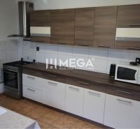 Küche in einem Einfamilienhaus mit Holzdekor, Kochfeld, Mikrowelle, Ventilator.