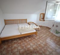 Schlafzimmer im Einfamilienhaus mit Keramikfliesen, Bett und offenem Fenster.