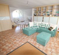 Wohnzimmer in einem Einfamilienhaus mit Ecksofa und Fliesenboden.