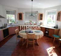 Küche in einem Einfamilienhaus mit Holzdekor, Esstisch und Fliesenboden.
