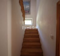 Eine Treppe in einem Einfamilienhaus mit einem Boden in Holzoptik und einem Fenster an der Wand.