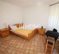 Schlafzimmer mit Bett, Holzmöbeln und Fliesenboden in einem Einfamilienhaus.