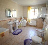 Geräumiges Badezimmer mit zwei Waschbecken, Badewanne und Fenster in einem Einfamilienhaus.