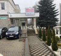 Gebäude in der SNP-Straße in Snina mit Parkplatz und Werbung für die Vermietung von Räumlichkeiten.