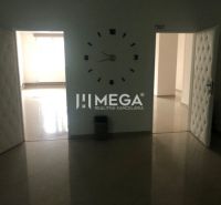 Innenraum eines Gebäudes mit auffälliger Uhr an der Wand und offenen Türen.