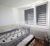 Schlafzimmer in einer 2-Zimmer-Wohnung mit Heizkörper und Bett, Boden mit Holzdekor.