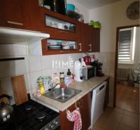 Küche in einer 2-Zimmer-Wohnung mit dunklen Möbeln und Küchengeräten.